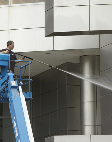 SoCal Property Services worker pressure washing a commercial building exterior