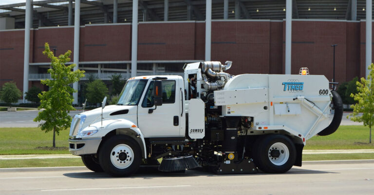 Tymco sweeper truck sweeps the street at a large athletic facility